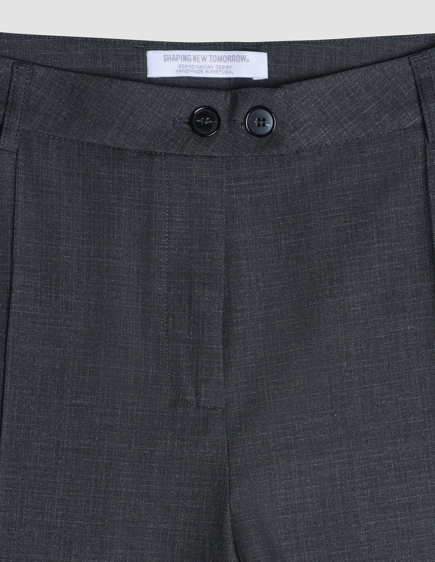 Nahaufnahme der Damenhose „Nara“ in gerader Passform, Farbe „Grey Flint“, mit einem „Shaping New Tomorrow“-Markenlabel und zwei schwarzen Knöpfen am Bund.